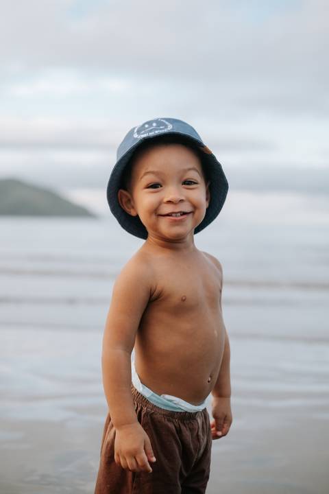 Foto aproximada do bebê de chapéu azul com expressão alegre.'