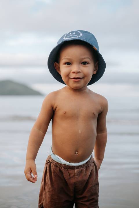 Foto de close do tronco e rosto do bebê olhando pra câmera. '