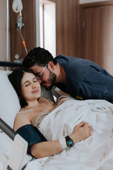Foto do pai abraçando a mãe em um momento de alívio e comemoração.'