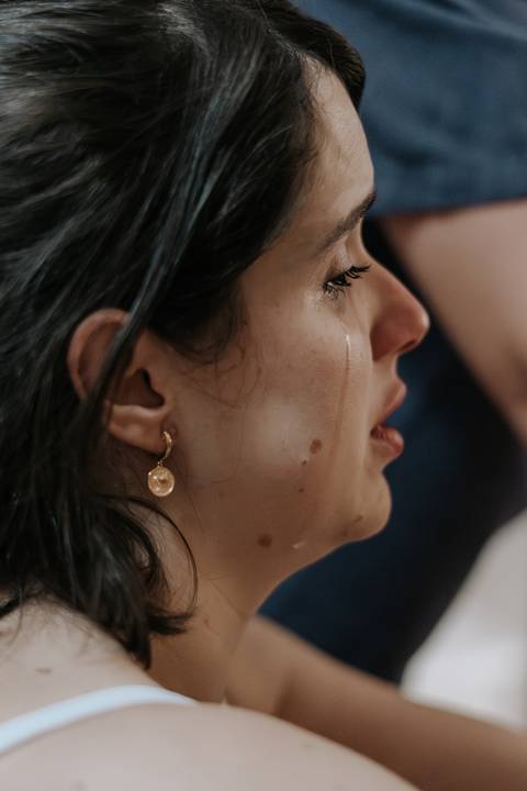Foto de close do rosto da gestante com lágrimas, expressando a intensidade do momento.'