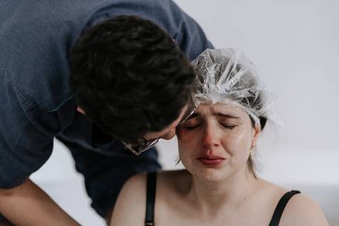 Foto da gestante emocionada sendo abraçada pelo companheiro.'
