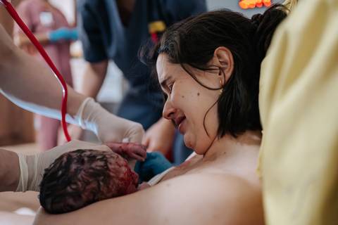 Foto do momento exato do nascimento, com a mãe vendo o bebê pela primeira vez.'
