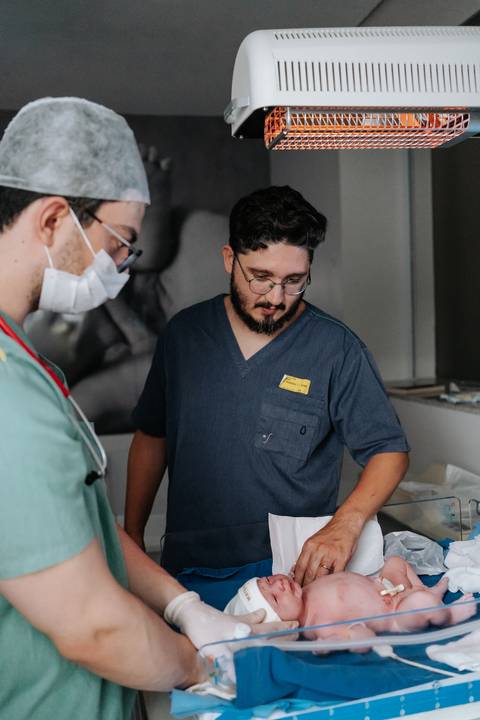 Foto do pai observando o trabalho da equipe médica durante os procedimentos.'