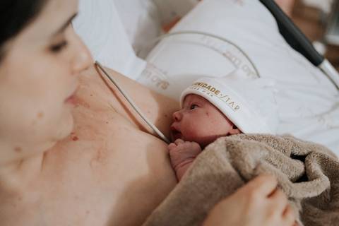 Foto de close da mãe iniciando a primeira amamentação na 
