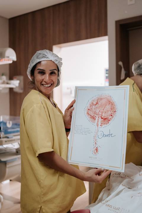 Foto de profissional da saúde exibindo a impressão da placenta em papel (Árvore da Vida).'