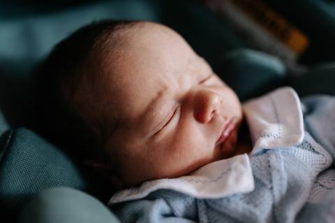 Foto de close do bebê recém-nascido dormindo tranquilamente no bebê-conforto.'