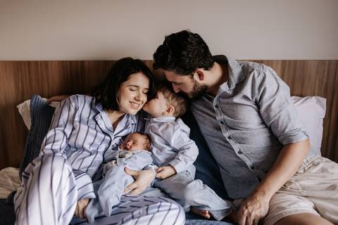 Foto da família trocando carinhos e beijos em um momento espontâneo.'