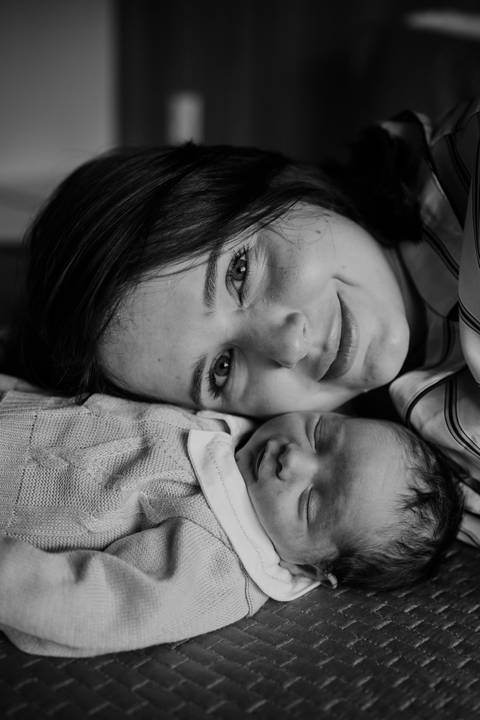 Foto em preto e branco da mãe e bebê de rostinhos colados. '