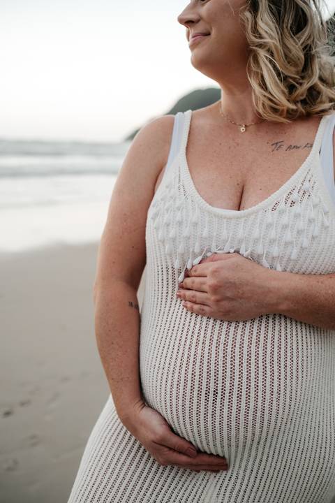 Close do detalhe da mão da gestante sobre a barriga.'