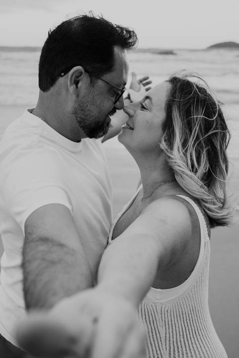 Foto em preto e branco de close do casal quase se beijando na praia.'