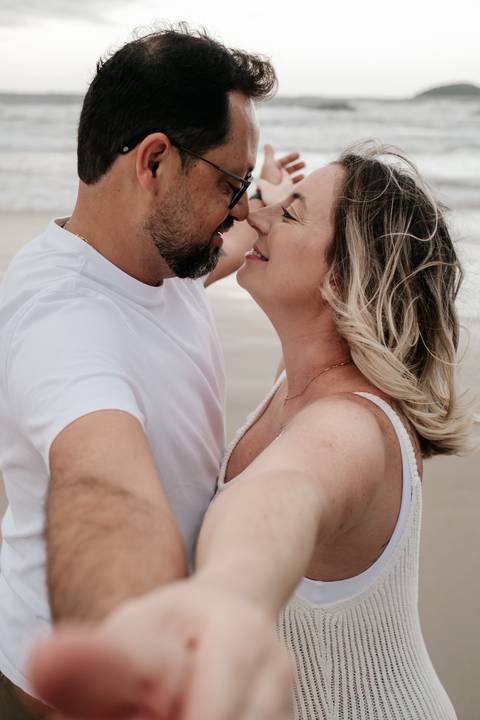 Foto colorida de close do casal sorrindo um para o outro em momento romântico.'
