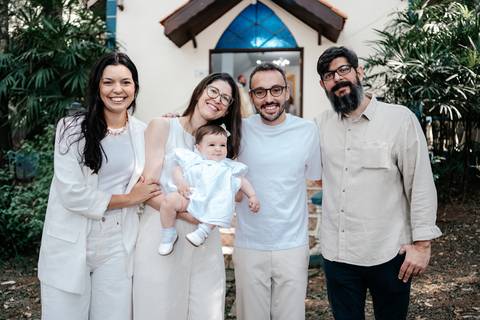 Retrato da família estendida (padrinhos/familiares) posando unida no dia do batismo.'