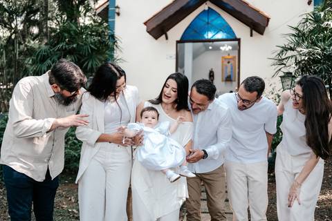 Foto espontânea de toda a família reunida conversando e sorrindo com a bebê ao centro.'