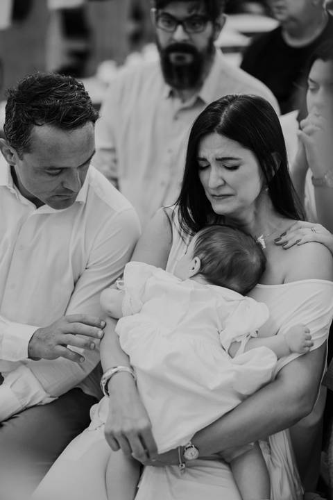 Foto em preto e branco capturando a forte emoção e sensibilidade da mãe com a bebê no colo.'