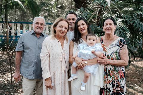 Retrato da família reunida com os avós em meio à natureza do jardim.'