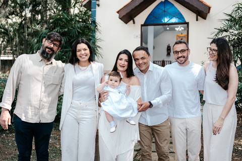 Retrato oficial com os padrinhos e familiares reunidos em frente à capela.'