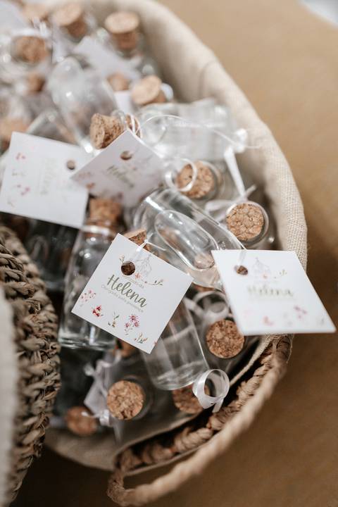Detalhe dos potinhos de água benta com tags personalizadas com o nome 