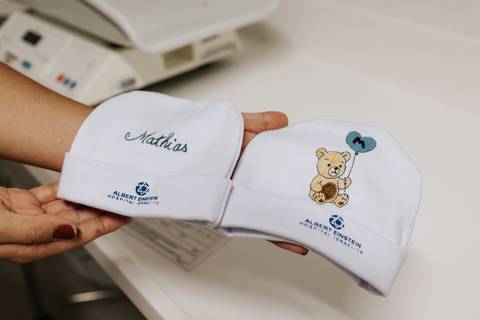 Detalhe das duas touquinhas brancas personalizadas com o nome 