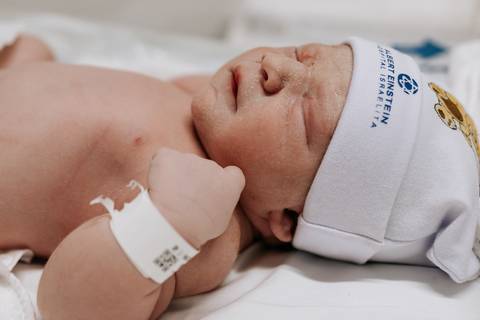 Close de perfil do bebê Mathias com os punhos cerrados durante os primeiros exames.'