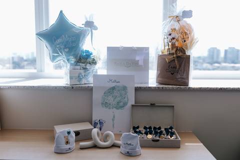 Foto dos detalhes decorativos da maternidade, incluindo balão, quadro e lembrancinhas.'