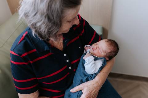 Foto aproximada de outra avó segurando Mathias no colo com muita ternura.'