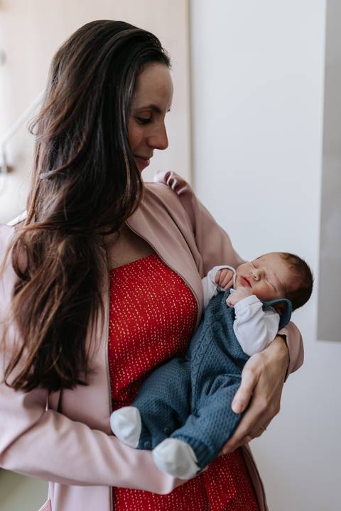Foto da médica de perfil segurando o bebê Mathias adormecido no colo.'