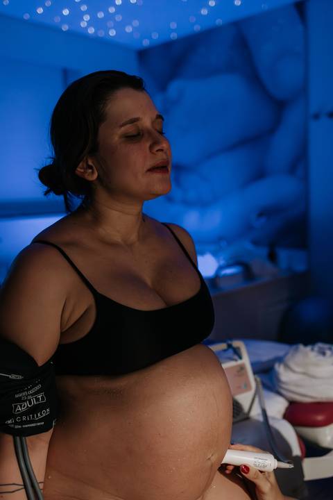 Foto aproximada de perfil da gestante concentrada sob uma iluminação azul suave.'