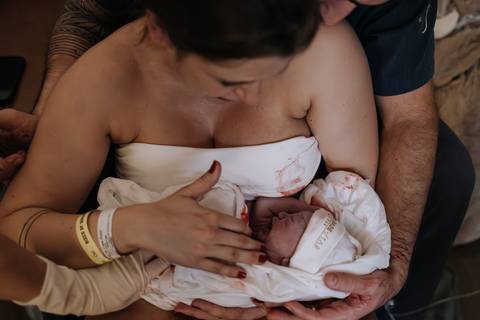 Foto do momento exato em que o bebê nasce e é colocado diretamente sobre o colo da mãe.'