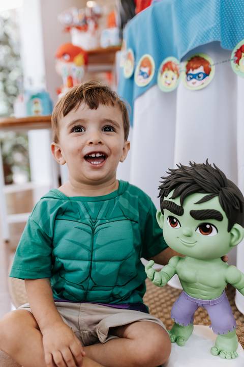 Close-up do aniversariante caçula sorrindo com os olhos brilhando ao lado de um boneco do Hulk.'