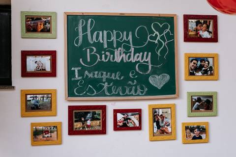 Foto de uma parede decorada com retratos da família ao redor de uma lousa escrito 