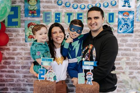 Retrato oficial do casal com os dois filhos em frente aos bolos de aniversário de 2 e 5 anos.'