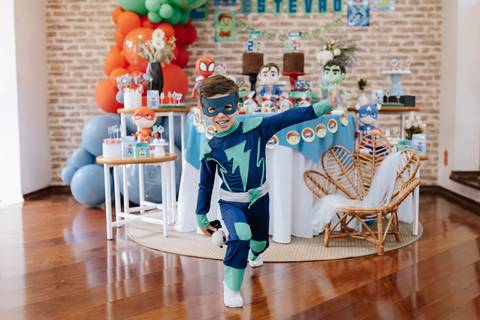 Foto em ângulo aberto do filho mais velho fazendo pose dinâmica de herói no meio do salão.'