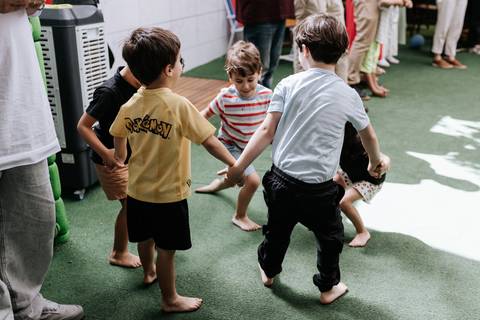 Registro de ângulo superior das crianças brincando de roda de mãos dadas no espaço externo.'