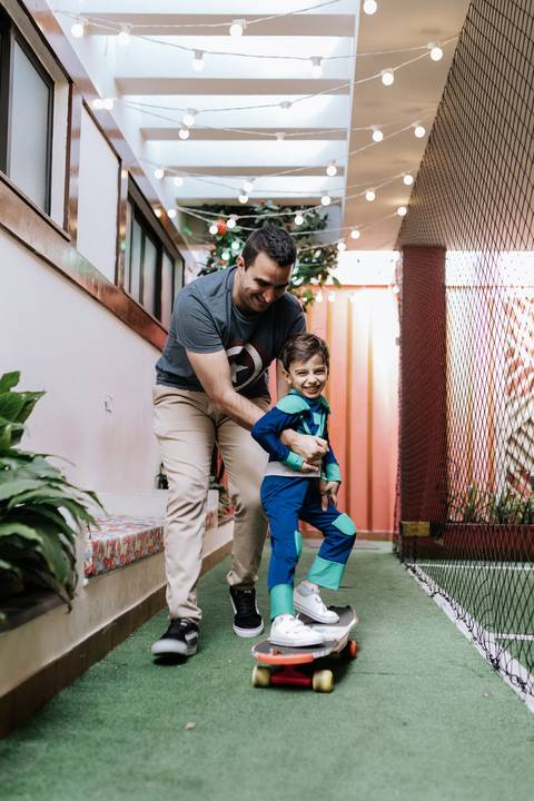 Registro do pai brincando com o filho mais velho no pátio do buffet.'
