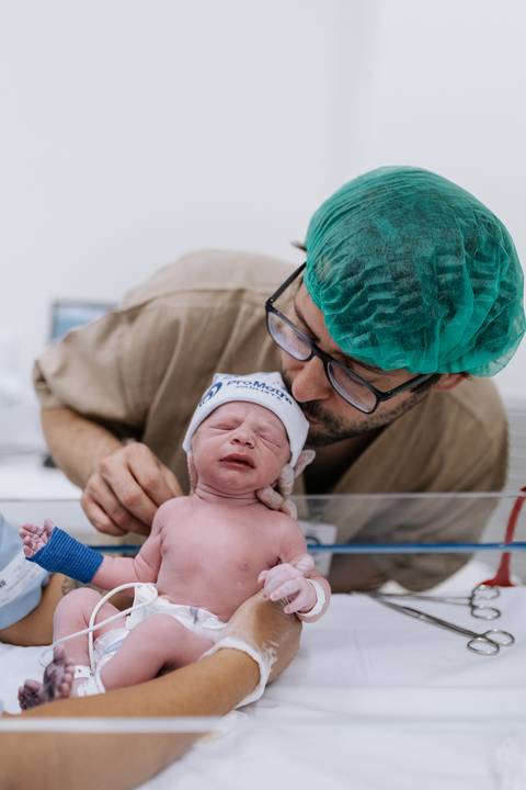 Foto de pai emocionado ao lado do recém-nascido na maternidade'