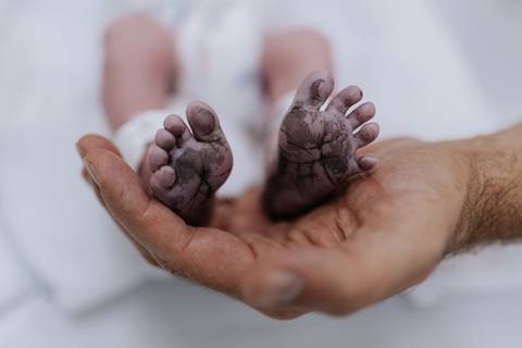 Foto de detalhe dos pés do recém-nascido nas mãos do pai'