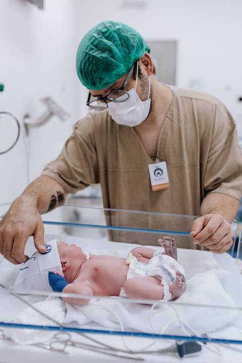 Foto de pai acompanhando os primeiros cuidados do recém-nascido'