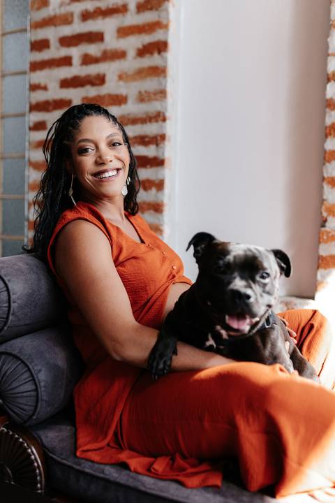 Close da gestante sentada sorrindo com seu cachorro no colo. '