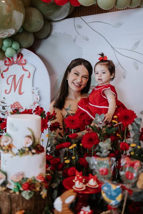 Mãe e filha sorrindo ao lado do bolo de aniversário.'