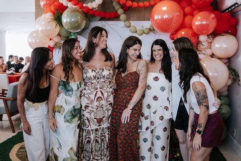 Grupo de amigas e convidadas reunidas sorrindo no salão.'