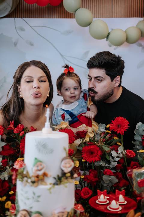 Pais com a bebê vestida de Branca de Neve na hora do parabéns.'