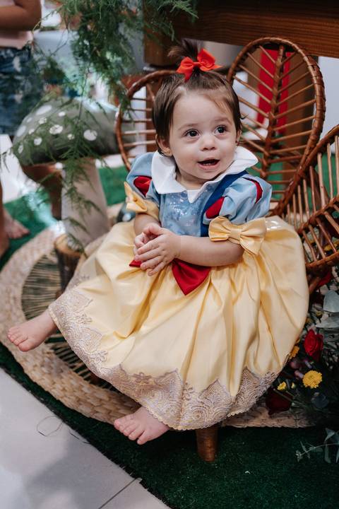 Close do vestido clássico de Branca de Neve da aniversariante sentada.'