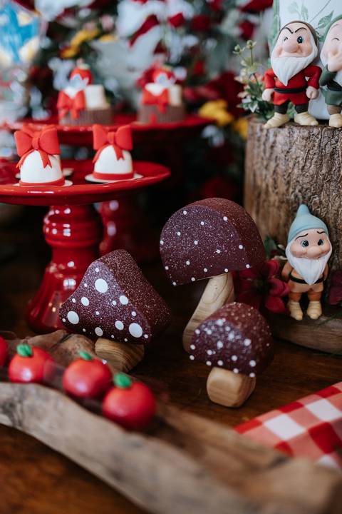 Detalhe de bombons em formato de cogumelos marrons ao lado de um bonequinho de gnomo.'