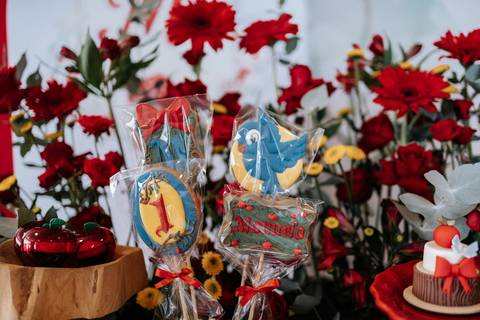 Pirulitos decorados com o número 1 em destaque em meio a flores vermelhas.'