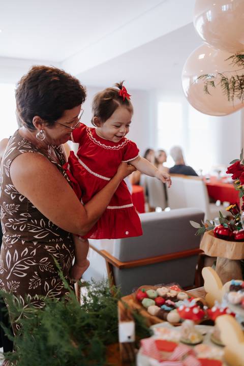 Bebê no colo de uma convidada interagindo alegremente durante a comemoração.'