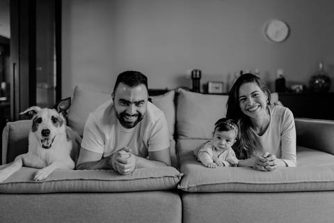 Versão em preto e branco da família e do cachorro deitados no chão em frente ao sofá.'