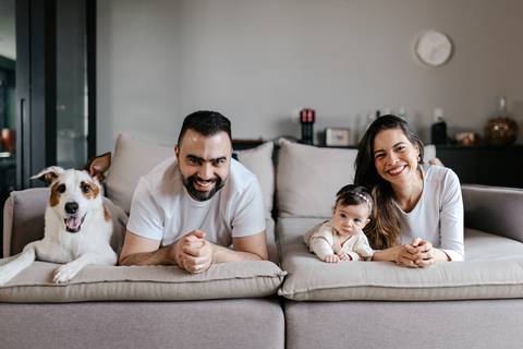 Retrato colorido da família e do cachorro deitados juntos na sala de estar.'