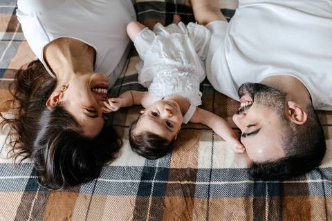 Registro aéreo da família olhando para a câmera e sorrindo na cama de casal.'