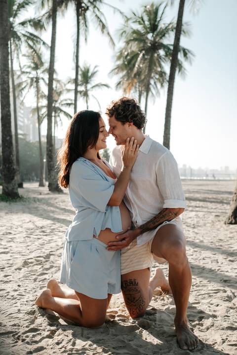 Retrato aproximado do casal sorrindo com os rostos bem próximos na praia.'