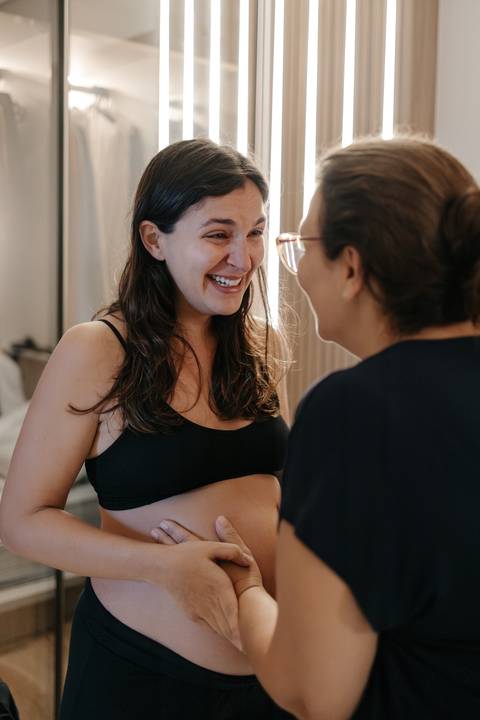 Gestante sorrindo e conversando com a profissional de saúde ou doula.'